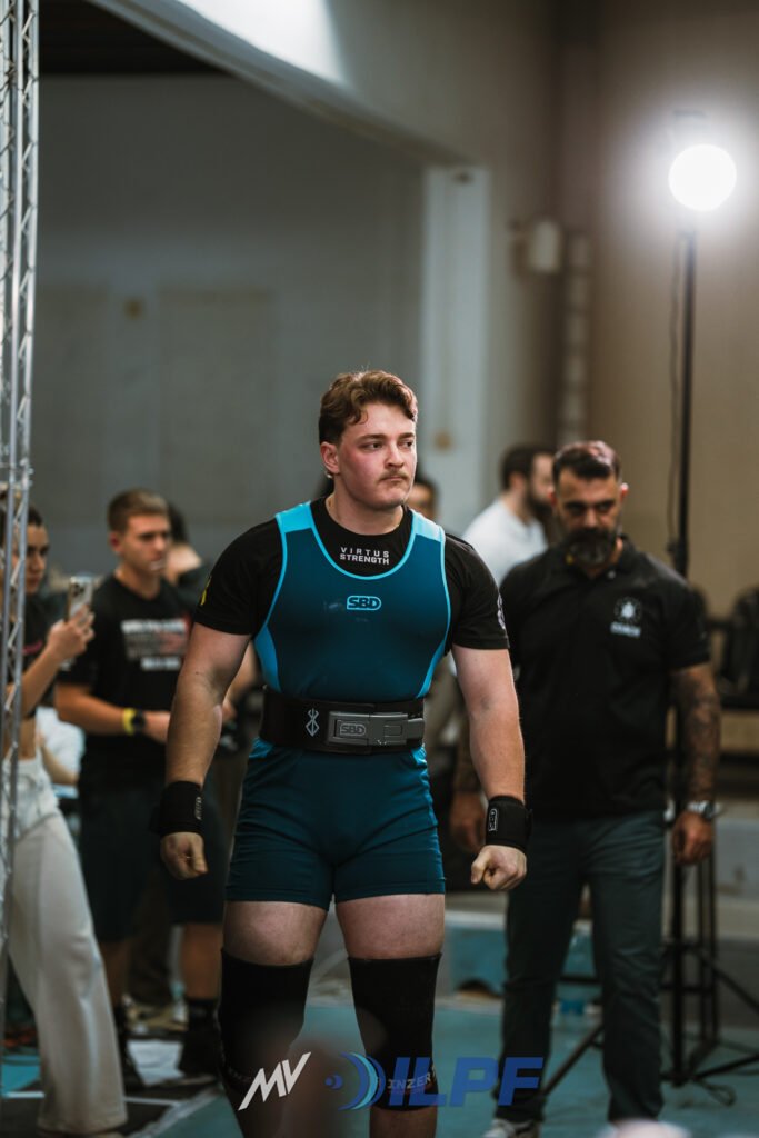 Alex Lysenko preparing to lift at a national powerlifting competition, representing Kaizen Strength Systems