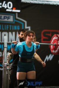 Female powerlifter coached by Kaizen Strength Systems preparing to squat at national competition