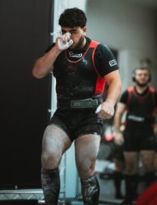 Kaizen Strength Systems athlete preparing for a lift at a national powerlifting event, covered in chalk