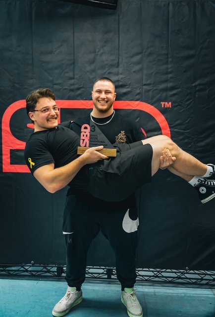 National powerlifting champion Alex Lysenko celebrating with a teammate after podium finish